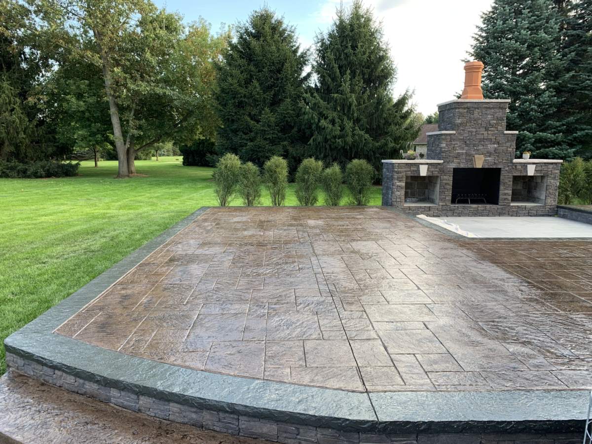Sealed pattern imprinted concrete patio in an ashlar slate pattern, laid around an outdoor fireplace